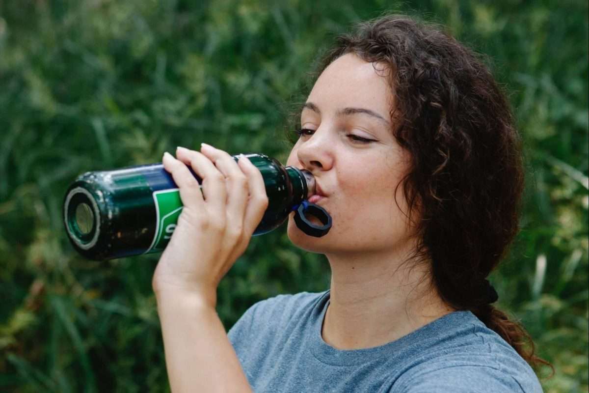 woman drinking water from a bottle in the garden